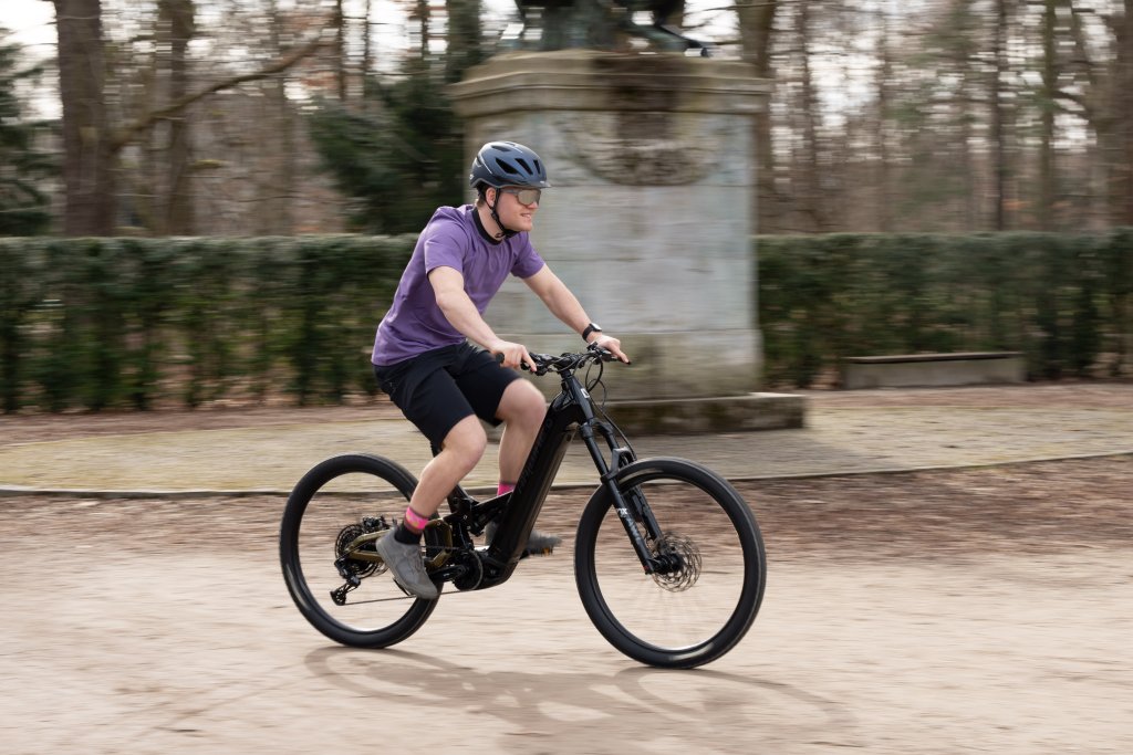 Mann fährt auf einen E-Mountainbike über einen Platz.