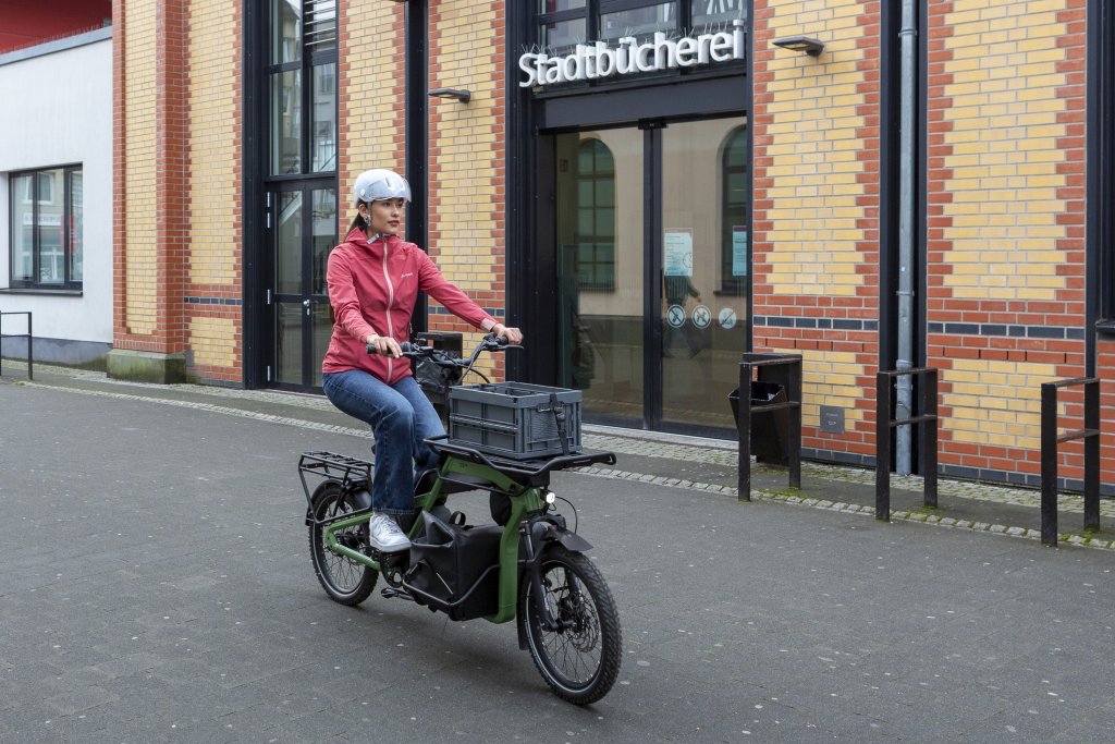 Frau fährt mit Lastenrad durch Stadt.