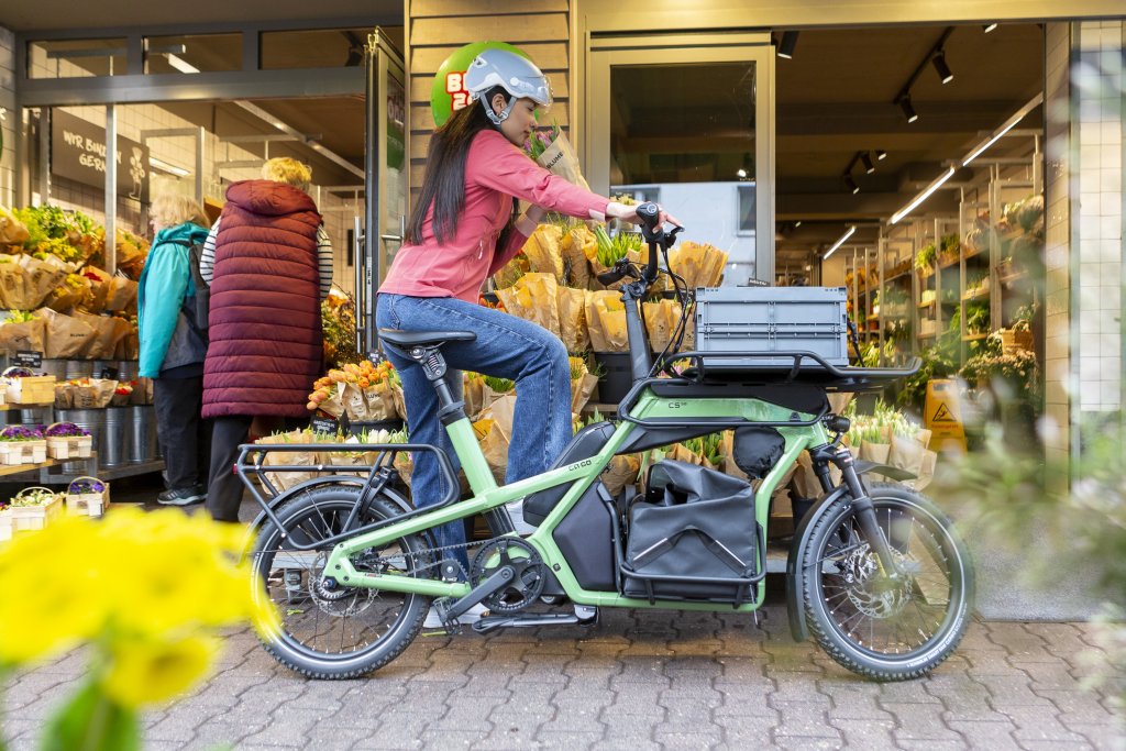 Frau steht mit Lastenrad an Blumenladen.