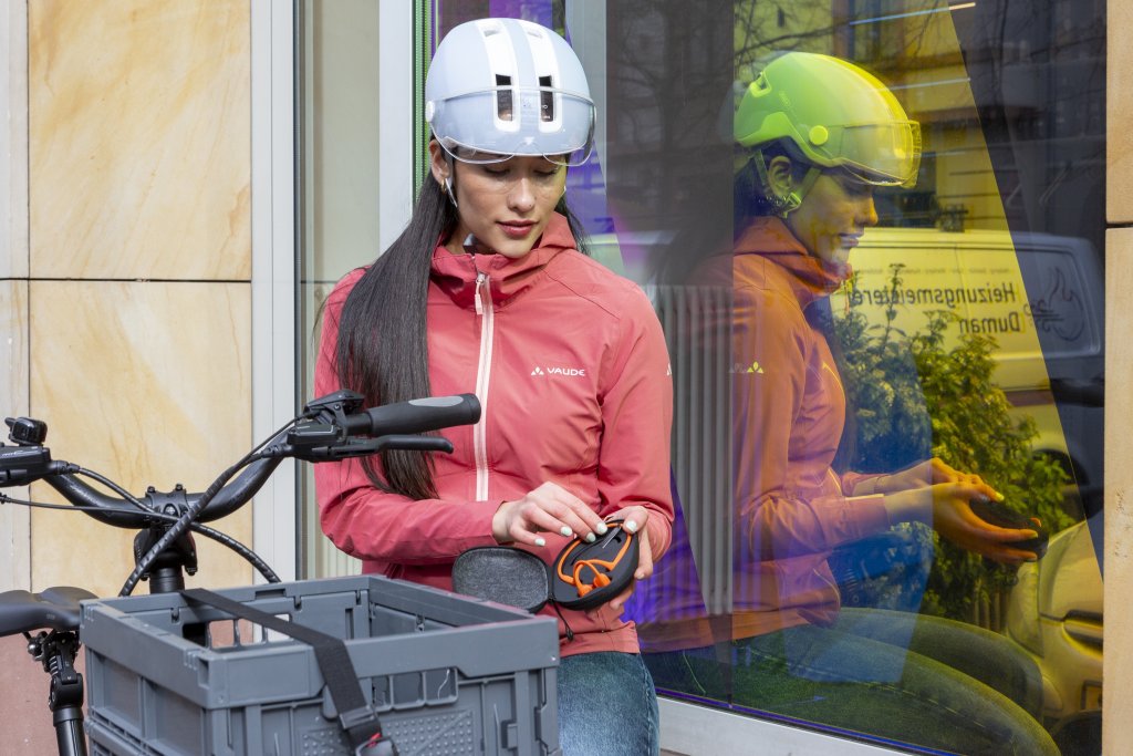 Frau packt Kopfhörer neben Fahrrad aus.