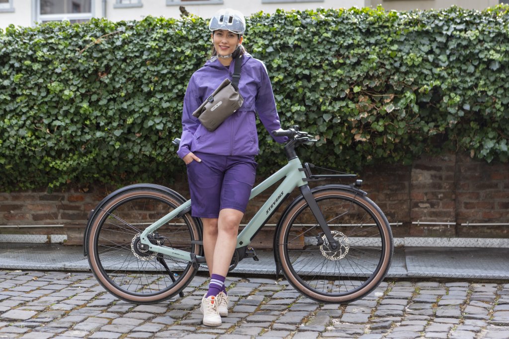 Frau lehnt mit Umhängetasche an einem E-Bike.
