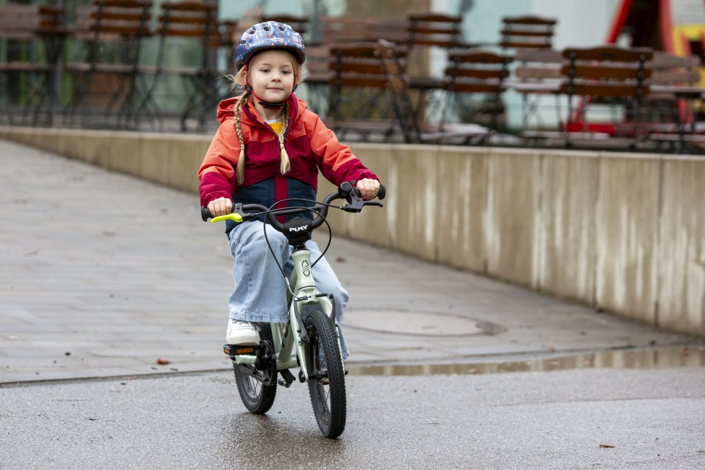Kind fährt mit einem Fahrrad durch einen Park.