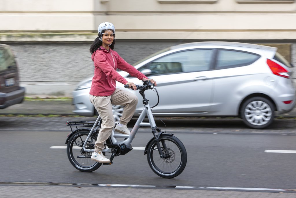 Frau fährt auf einem E-Kompaktbike durch die Stadt.