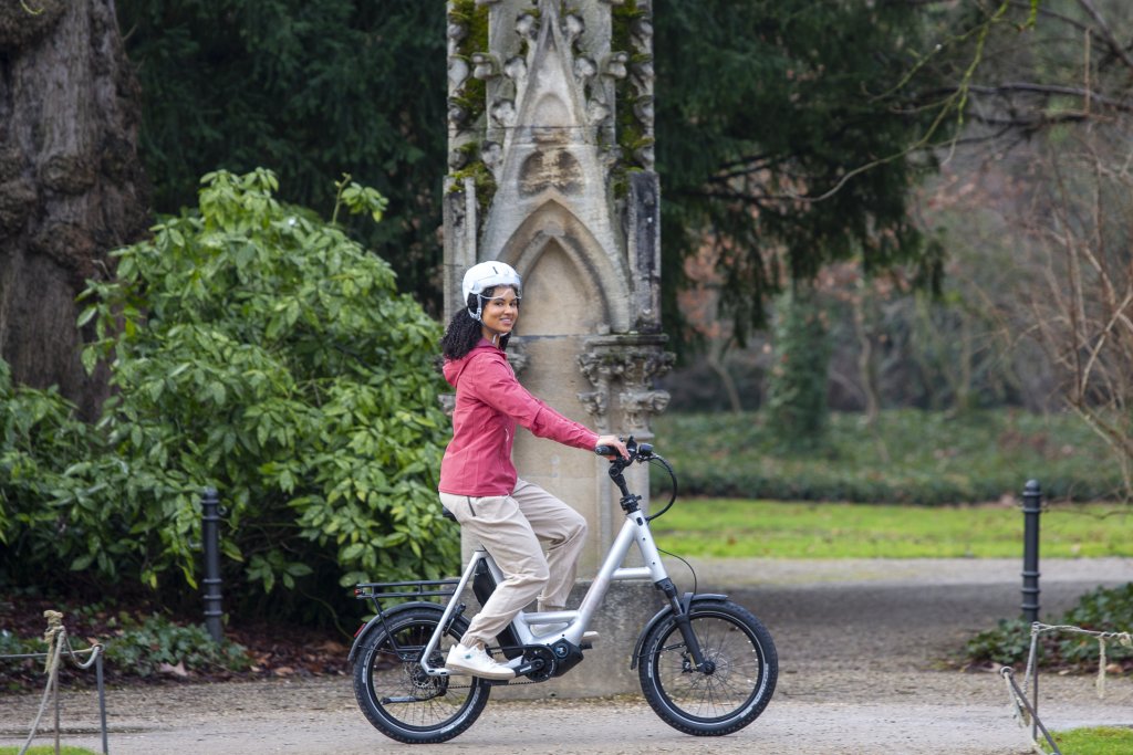 Frau fährt mit einem E-Bike durch einen Park.