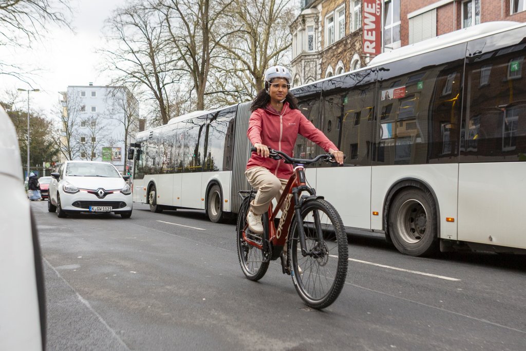 Frau fährt mit E-Bike an einem Bus vorbei.