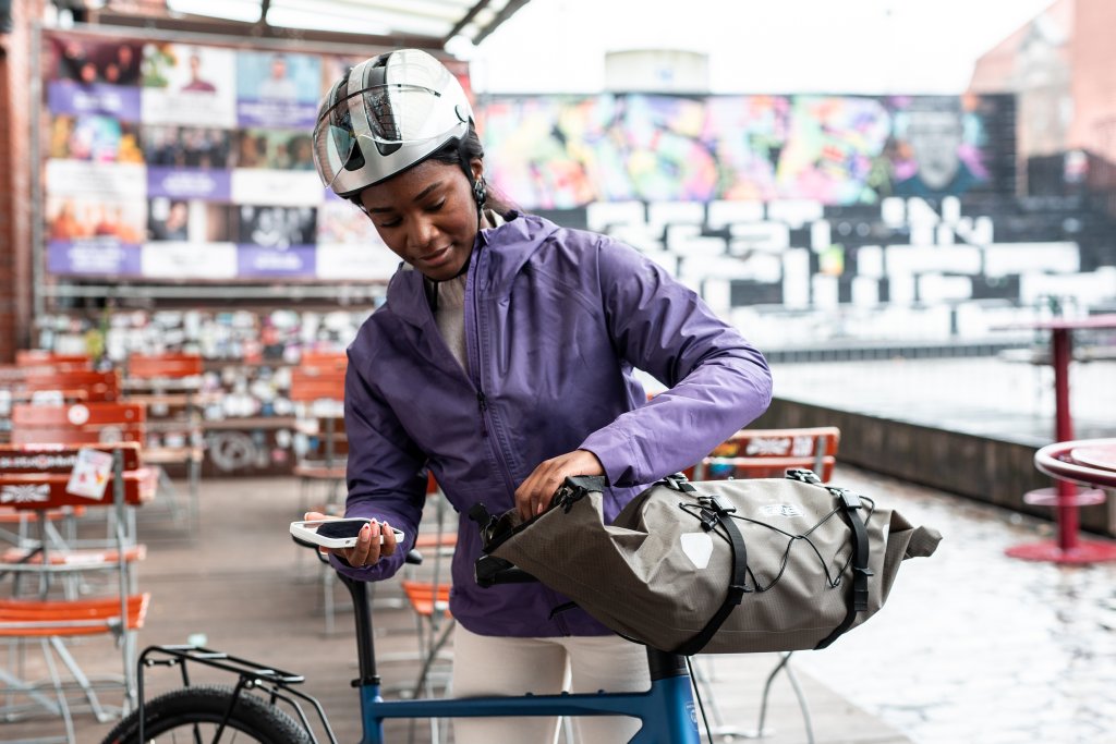 Frau bepackt Lenkertasche an Fahrrad.