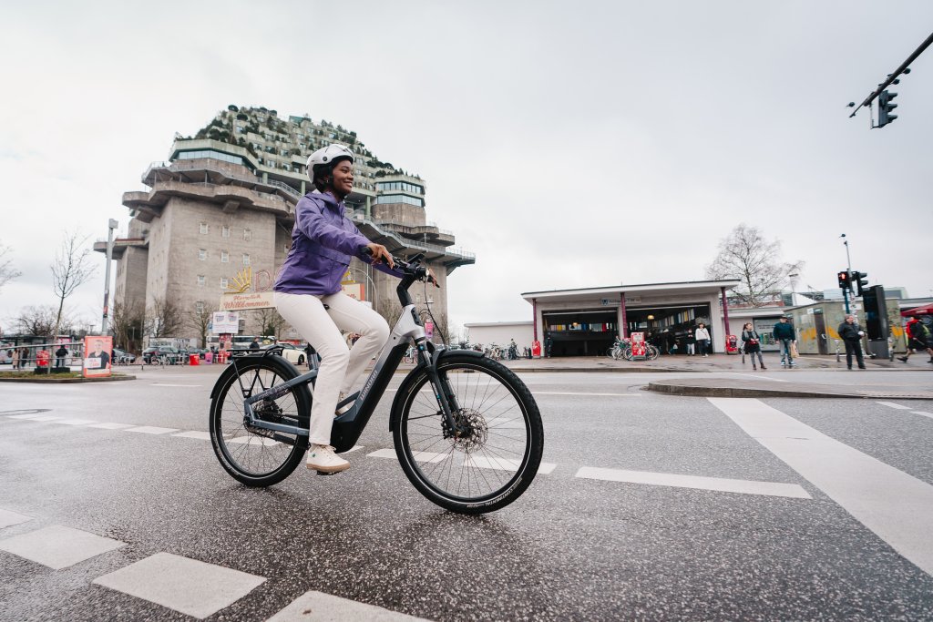 Frau fährt mit E-Bike durch Stadt.