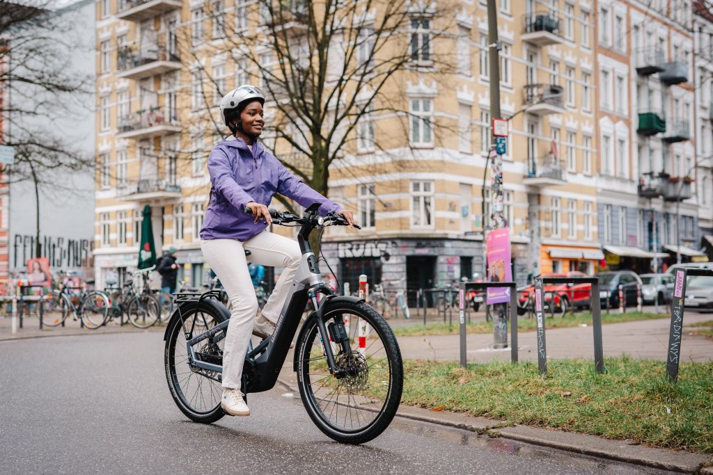 Frau fährt mit E-Bike durch die Stadt.