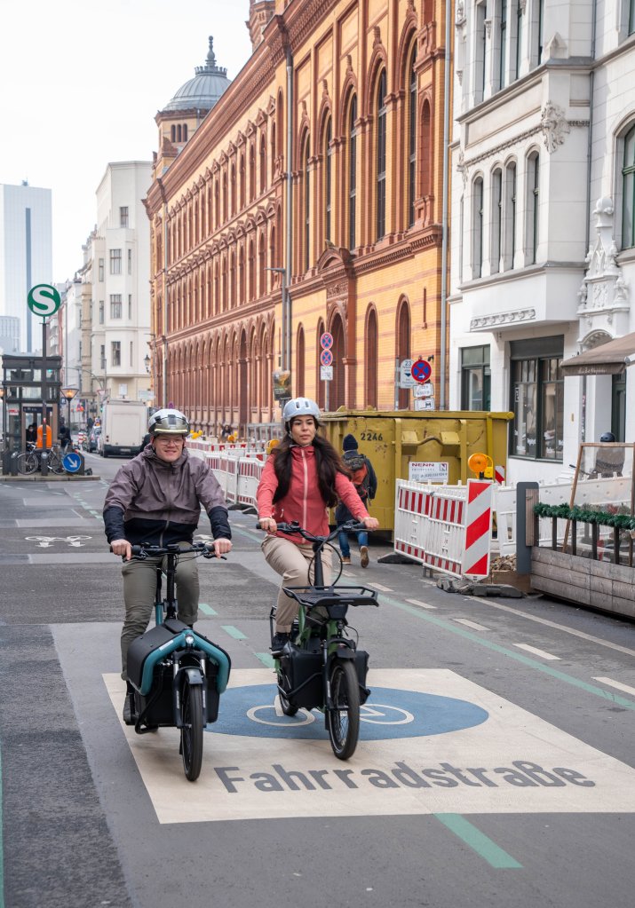 Frau und Mann fahren mit Lastenrädern durch Berlin.
