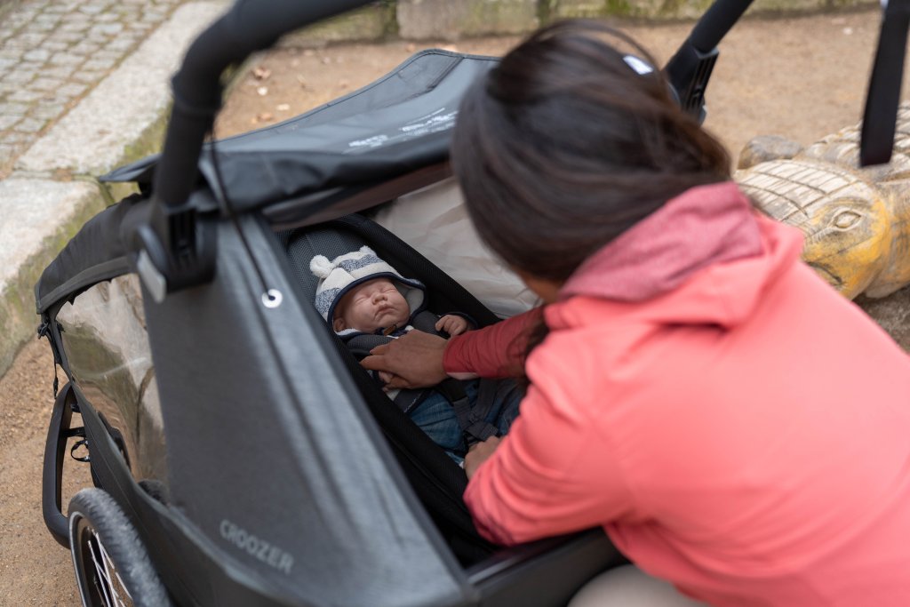 Frau nutzt einen Fahrradanhänger als Kinderwagen.