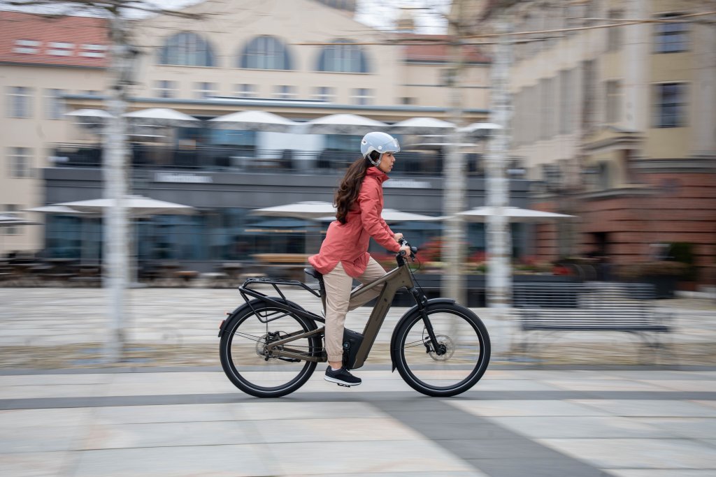 Frau fährt mit E-Bike durch eine Stadt.