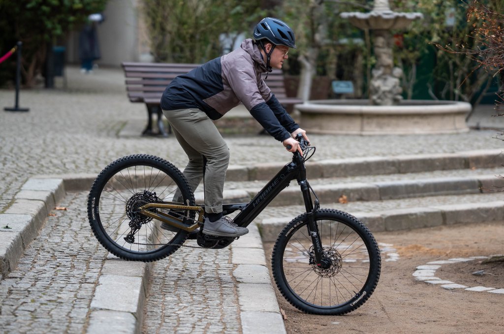 Mann fährt mit E-Bike über Treppenstufen.
