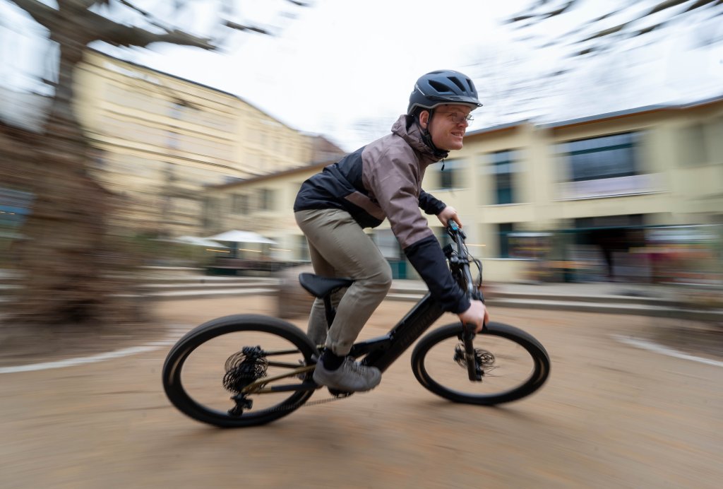 Mann fährt mit E-Mountainbike schnell in einem Hof.