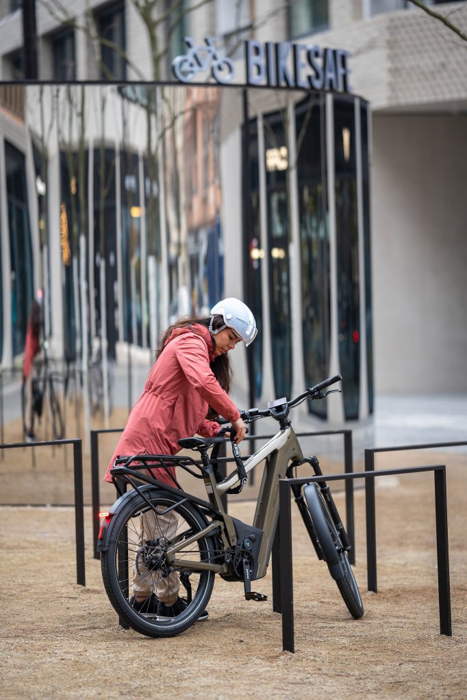 Frau stellt E-Bike an Fahrradständer ab.