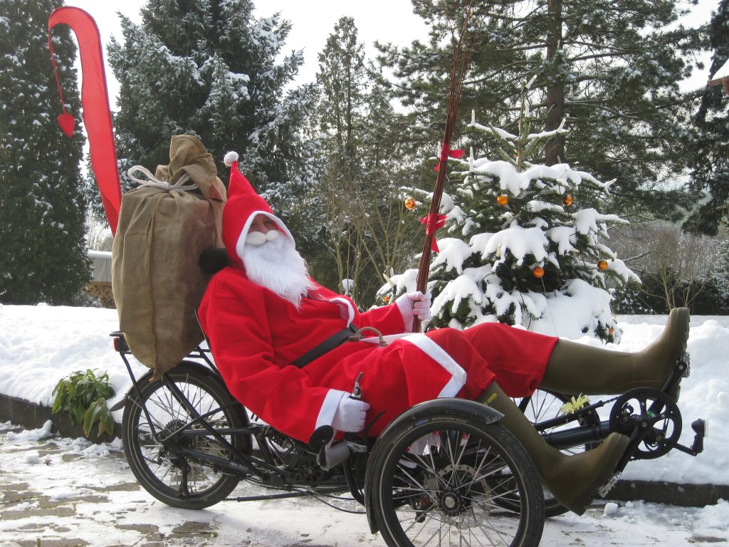 Eine als Weihnachtsmann verkleidete Person auf einem Liegedreirad.