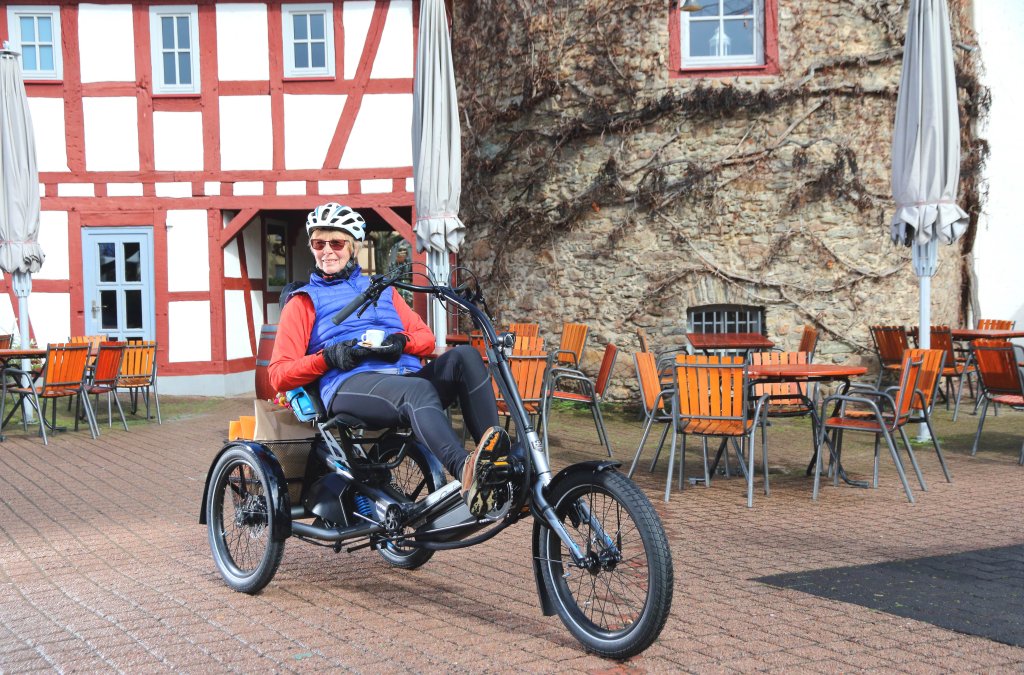 Eine Person auf einem Liegedreirad in einer Altstadt.