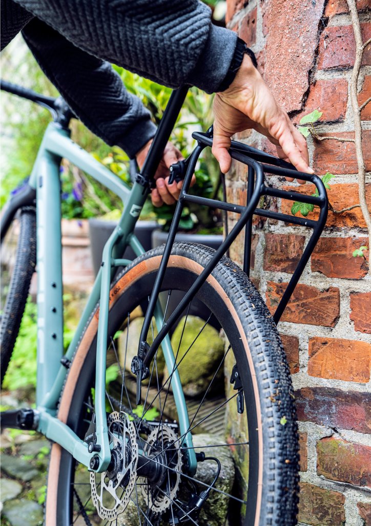 Eine Person montiert einen Gepäckträger mit Schnellverschlüssen an einem Fahrrad.