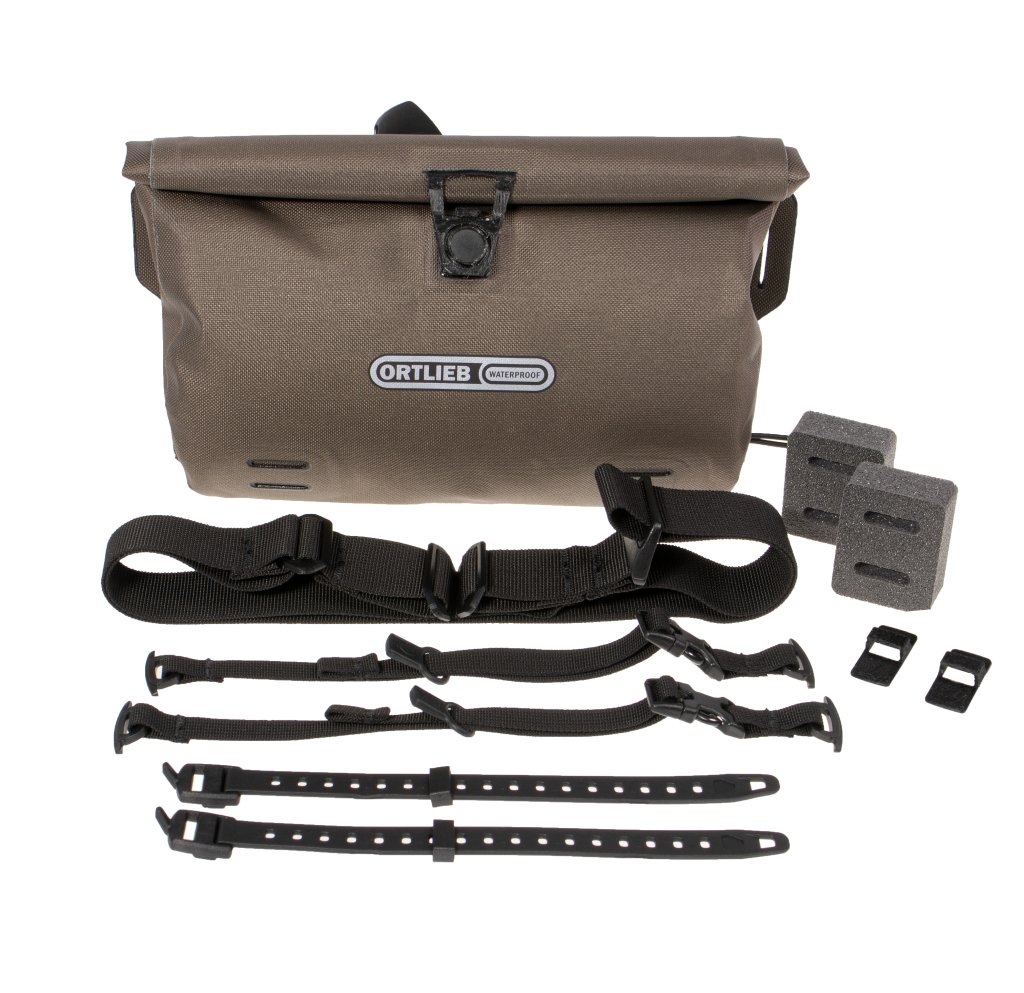 Lenkertasche im Hintergrund, davor sämtliches Zubehör wie Schnallen und Gurte.