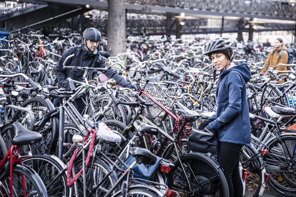 Zwei Personen mit Helmen stehen in einer großen Menge abgestellter Fahrräder.