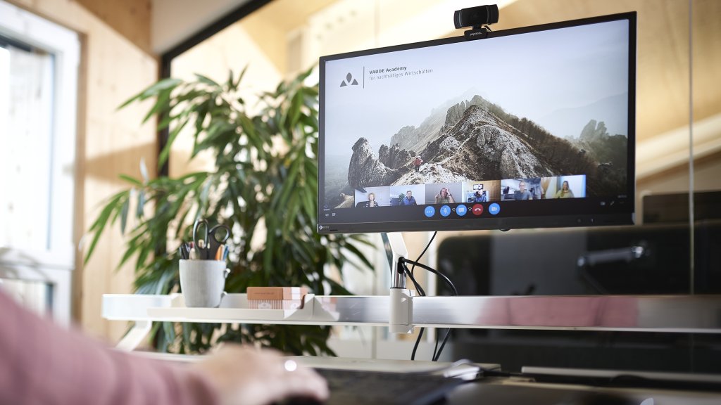 Ein Computerbildschirm in einem Büro, darauf ein Bergpanorama und das Firmenlogo von Vaude