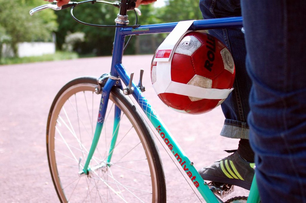 Ein roter Ball, mit Hilfe eines weißen Bandes im Rahmen eines Fahrrades befestigt.