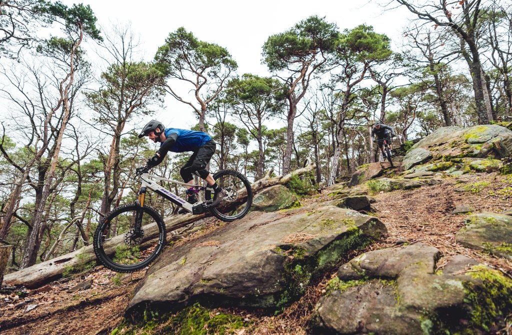 Zwei Personen fahren auf E-Mountainbikes in felsigem Gelände bergab.