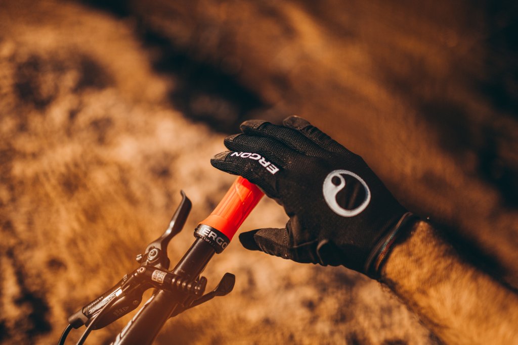 Eine Hand mit Handschuh greift nach dem Griff an einem Fahrradlenker.