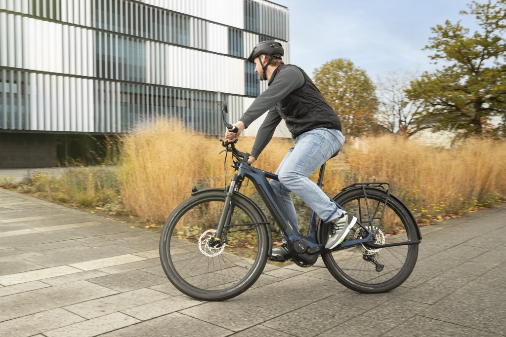 Ein Mann biegt auf einem E-Bike in Richtung eines Gebäudes ab.
