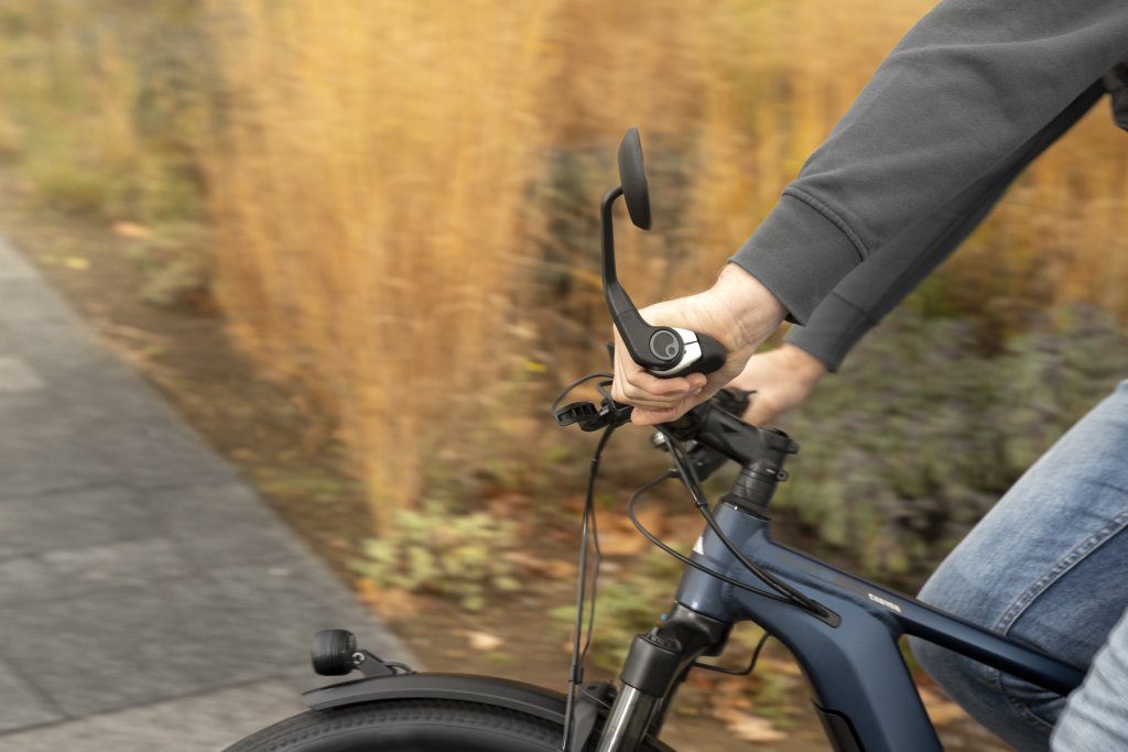 Seitenansicht eines Fahrradlenkers mit Rückspiegel am Lenkerende während der Fahrt