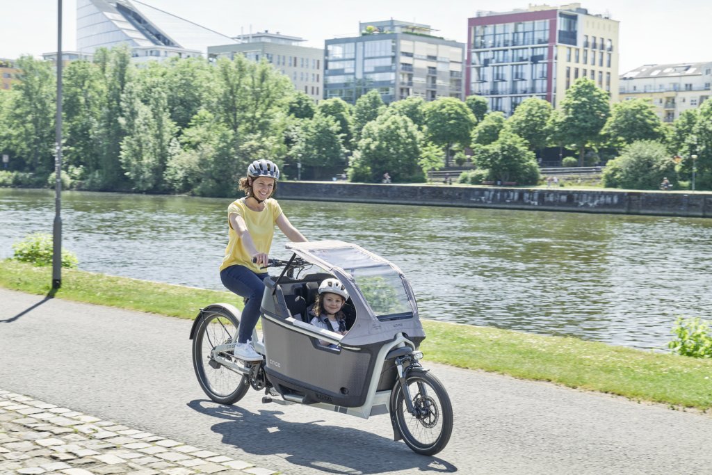 Frau fährt Kind in Lastenrad