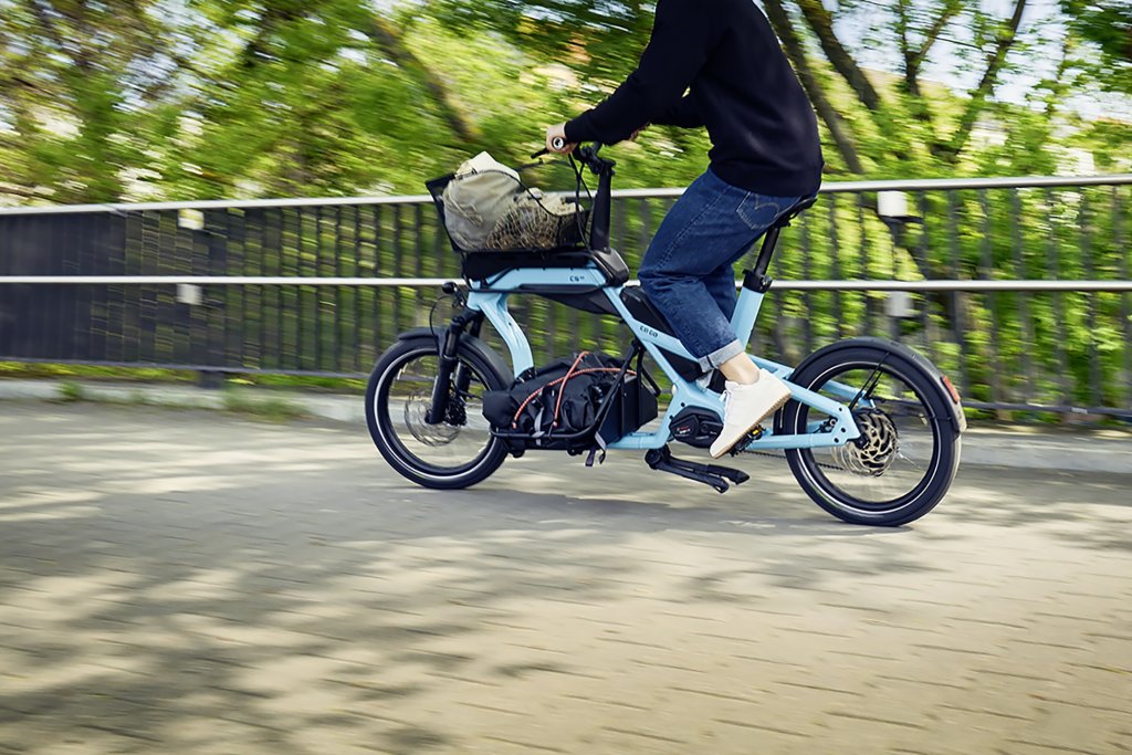 Mann fährt mit beladenem Cargobike durch die Stadt.
