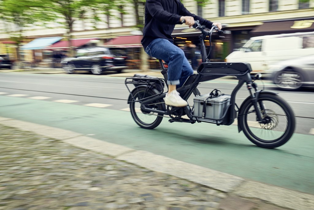 Mensch fährt beladenes Cargobike durch die Stadt.