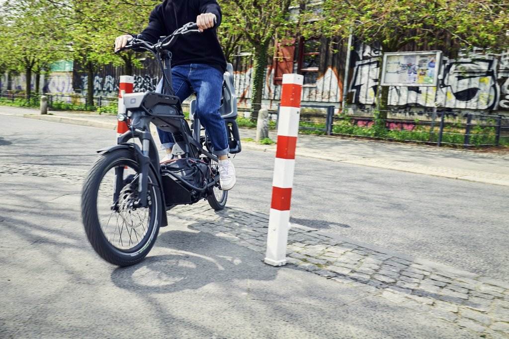 Mensch manövriert Cargobike durch Absperrungen.