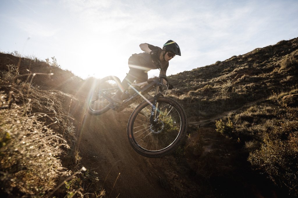 Eine Person springt auf einem Mountainbike eine Böschung runter.