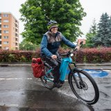 Ein Mann fährt bei Regen auf einem E-Bike durch ein Wohngebiet.