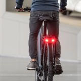 Am Gepäckträger eines Fahrrades leuchtet ein Bremslicht rot.