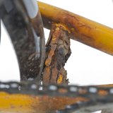 Eine rostige Verstrebung eines Fahrradrahmens mit abgeblättertem Lack.