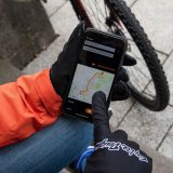 Ein Smartphone mit einer Navigations-App in der Hand einer Person mit Handschuhen.