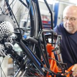 Ein Mechaniker arbeitet an einem Fahrrad oder Liegerad mit Hinterradmotor.