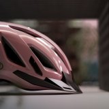 Ein rosa Fahrradhelm mit dem Logo der Firma Abus darauf, von der Seite betrachtet.