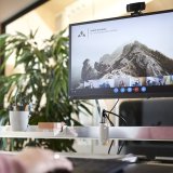 Ein Computerbildschirm in einem Büro, darauf ein Bergpanorama und das Firmenlogo von Vaude