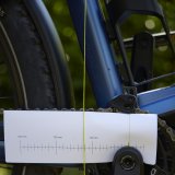 An der Kurbel eines E-Bikes ist ein Stück Papier mit einer aufgedruckten Skala platziert. Davor hängt ein Schnurlot.