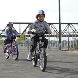 Zwei Kinder fahren auf Fahrrädern über einen Platz.