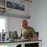 Ein Mann sitzt an einem Schreibtisch vor einem Laptop, der mit vielen Aufklebern verziert ist.