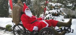 Eine als Weihnachtsmann verkleidete Person auf einem Liegedreirad.