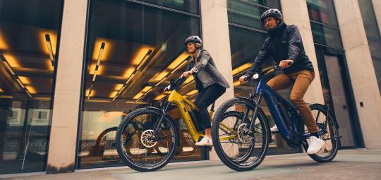 Paar fährt auf Fahrrädern nebeneinander durch die Stadt.