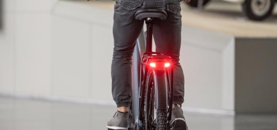 Am Gepäckträger eines Fahrrades leuchtet ein Bremslicht rot.