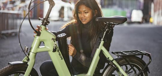 Eine Frau platziert den Akku eines E-Bikes im Rahmen.