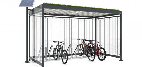 Ein überdachter Fahrradstellplatz mit Grünfläche auf dem Dach und einer Solarzelle daneben.