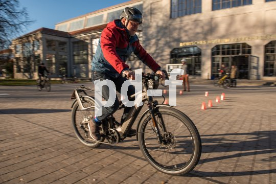 Ein Mann fährt auf einem gepflasterten Platz ein E-Bike.
